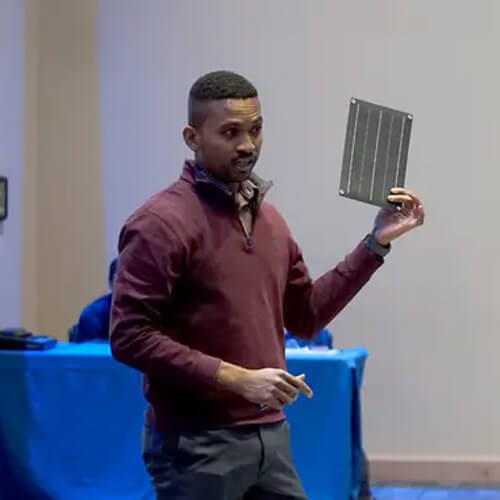 Graduate student Diego King, left, shows judges a solar panel that could help power his barReleeze system.
